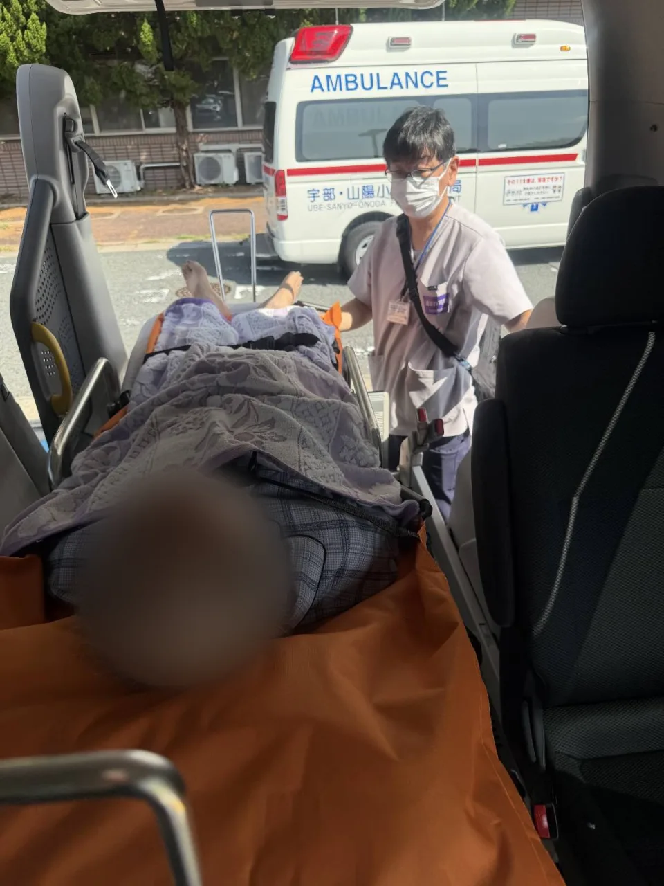 寝台福祉車両の車内で、ストレッチャーの方の乗り降りを介助する代表