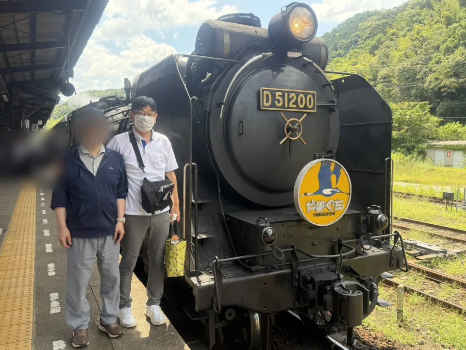 蒸気機関車の前で、ご利用者様と代表の記念写真