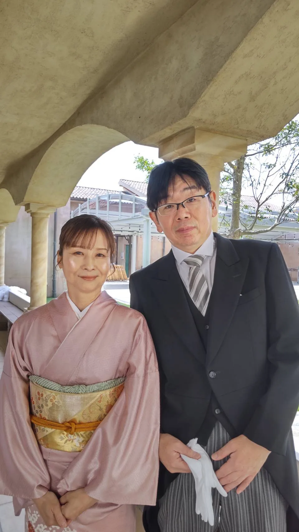 結婚式場の回廊に並ぶ、着物姿の女性とモーニングコート姿の男性